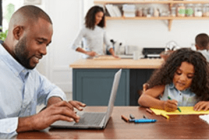 man working on a laptop with his family