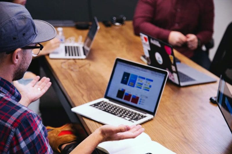 a group of people sitting at a table with laptops